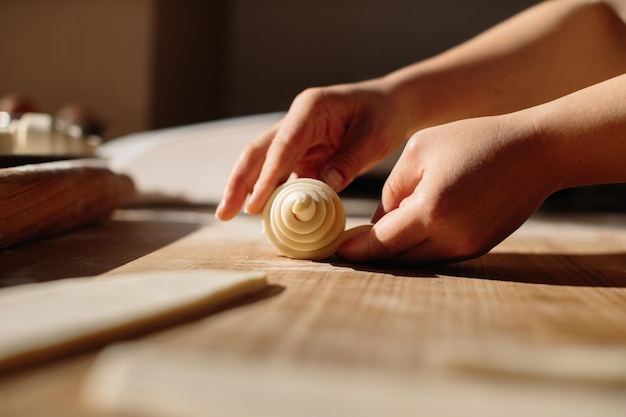 Mãos femininas rolando massa no processo de cozimento de rolos, fazendo croissant selecionado conceito de foco para padaria