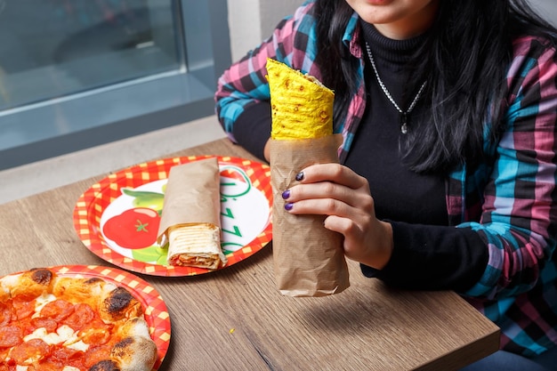 mãos femininas, segura shawarma de queijo e café, come, morde e vomita, fundo claro e escuro