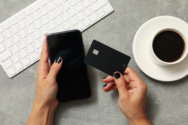 Mãos femininas seguram telefone e cartão cinza