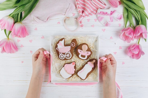 Mãos femininas segurando caixa com biscoitos. uma composição para recém-nascidos