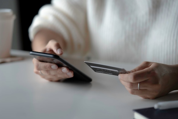 Mãos femininas segurando cartão de crédito e usando smartphone Compras online