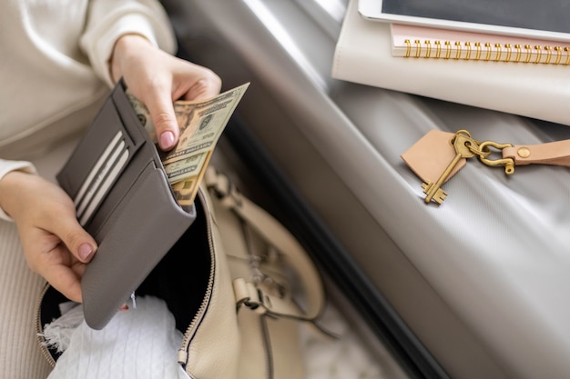 Mãos femininas segurando dinheiro, dólares na carteira, com cartões prontos para viagens de férias ou viagem de negócios