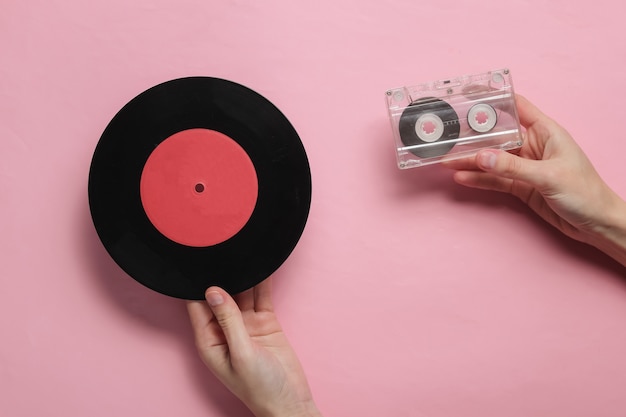 Mãos femininas segurando fita cassete e disco de vinil
