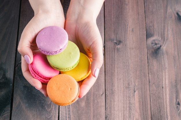 Mãos femininas segurando macarons