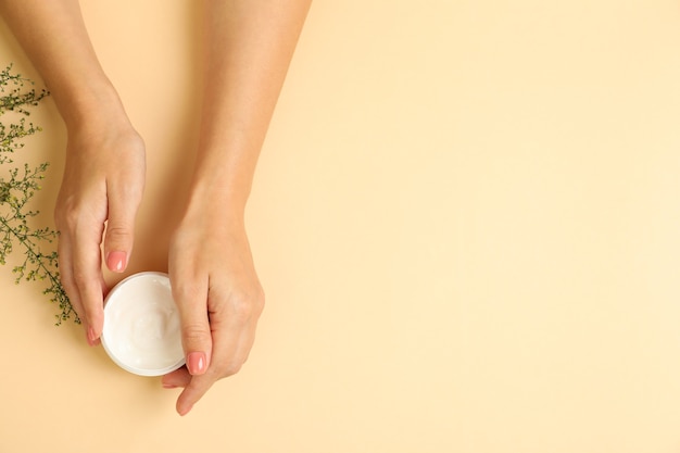 Mãos femininas segurando pote de creme cosmético isolado