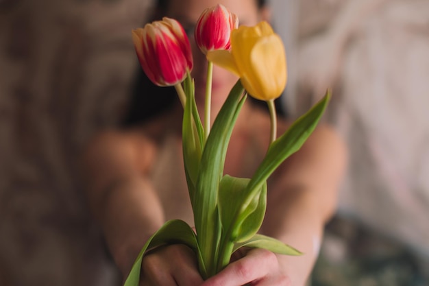 Mãos femininas segurando um buquê de tulipas amarelas de flores de primavera rosa Detalhes femininos de beleza
