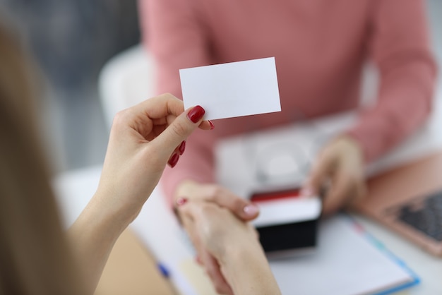 Mãos femininas segurando um cartão de visita branco