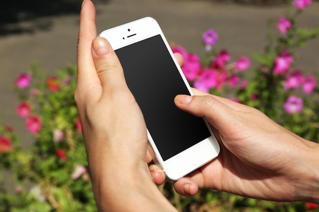 Mãos femininas segurando um celular inteligente ao ar livre