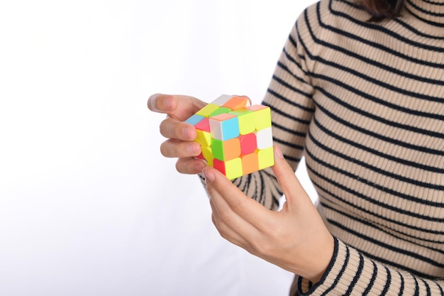 Mãos femininas segurando um cubo de quebra-cabeça em pé no fundo branco