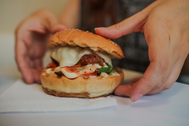 Mãos femininas segurando um delicioso hambúrguer fresco hambúrguer delicioso nas mãos refeição de fastfood