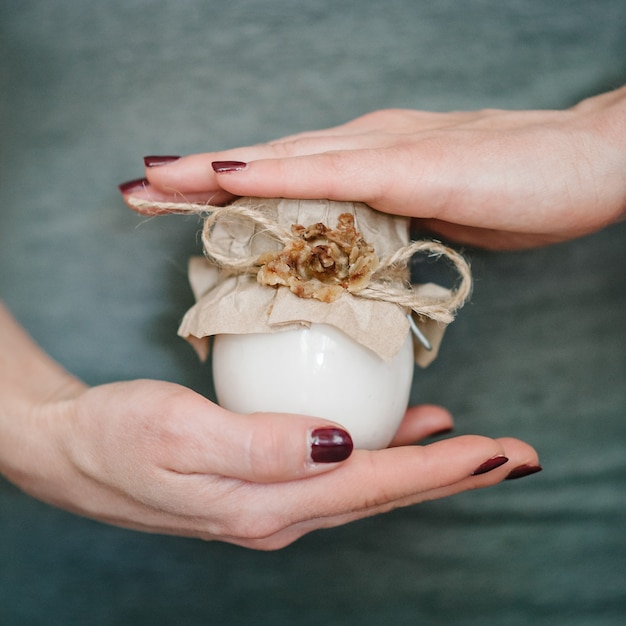 Mãos femininas segurando um frasco de creme hidratante cosmético