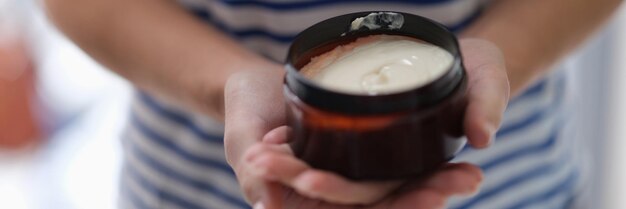 Mãos femininas segurando um frasco de máscara de cabelo, close-up