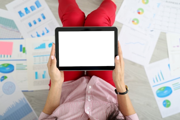 Mãos femininas segurando um tablet ao lado de gráficos