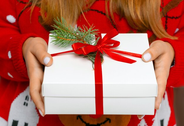Mãos femininas segurando uma caixa de presente de Natal