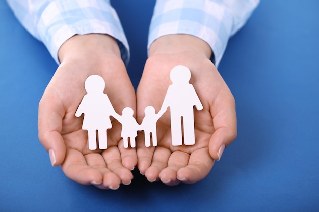 Mãos femininas segurando uma família de brinquedos na cor de fundo