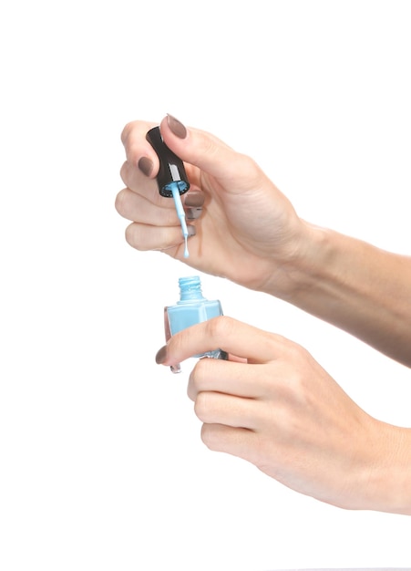 Mãos femininas segurando uma garrafa de esmalte de unhas isolada em fundo branco