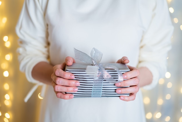 Mãos femininas segurar caixa de presente de Natal ou ano novo em fundo de boke Natal ano novo aniversário conc ...