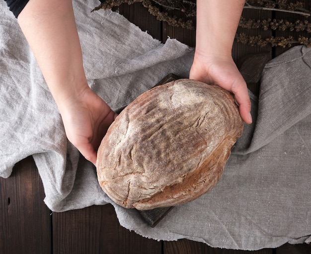 Mãos femininas, segure, um, inteiro, redondo, pão, de, pão centeio farinha