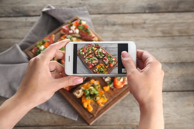 Mãos femininas tirando foto de comida com telefone celular