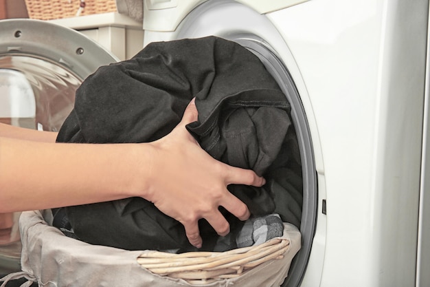 Mãos femininas tirando roupas limpas da máquina de lavar