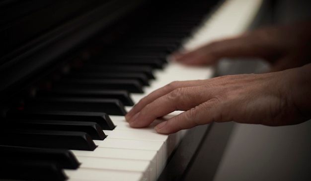 Mãos femininas tocam piano elétrico, as teclas das mãos e do piano fecham