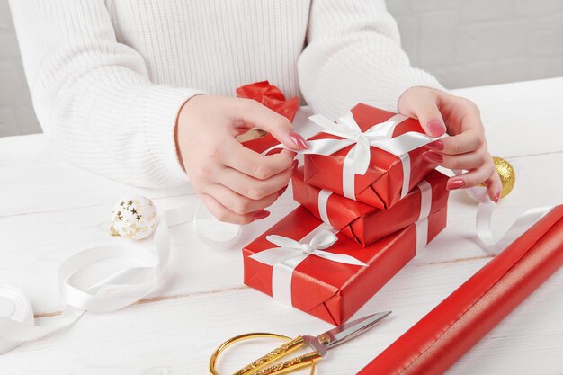 Mãos femininas tomando ou envolvendo o presente de Natal, aniversário ou dia dos namorados vermelho sobre um fundo branco, close-up. Temporada de férias e vendas