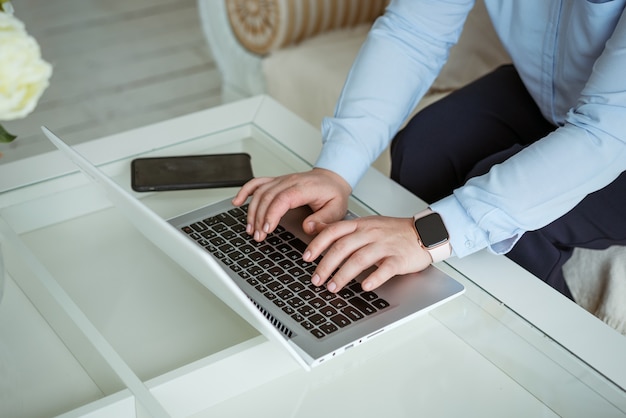 Mãos femininas trabalhando atrás de um laptop, sem rosto