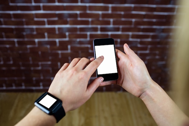 Mãos femininas usando smartphone e relógio inteligente