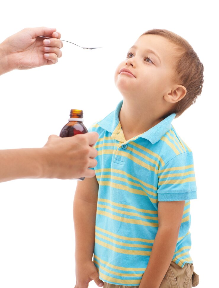 Foto mãos frasco de remédio e colher para menino no estúdio triste e pensando com a língua por fundo branco criança mãe e líquido para cuidados de saúde produto farmacêutico e ajudar criança doente para o bem-estar