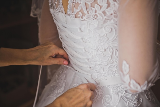 Mãos gentis de mães amarram o vestido de noiva em sua filha 2277