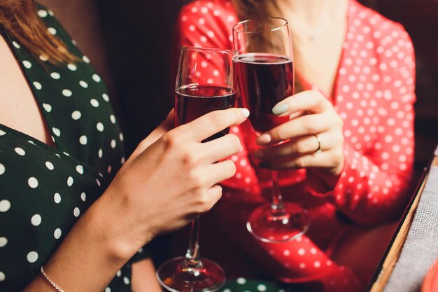 Mãos humanas com copos de vinho vermelho batendo-os sobre a mesa servida