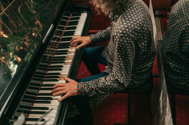 Mãos humanas de adulto maduro do sexo masculino tocando melodia nas teclas de piano ou piano de cauda. Foto de close-up