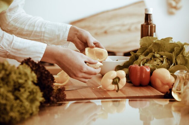 Mãos humanas desconhecidas cozinhando na cozinha. Mulher cortando pimentão amarelo. Refeição saudável e conceito de comida vegetariana.