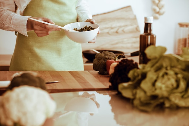 Mãos humanas desconhecidas cozinhando na cozinha. Mulher está ocupada com salada de legumes. Refeição saudável e conceito de comida vegetariana.