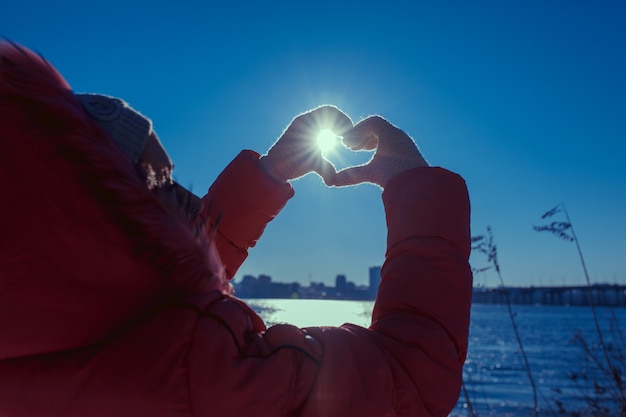 Mãos humanas gesticulando um sinal de amor sobre um fundo de sol