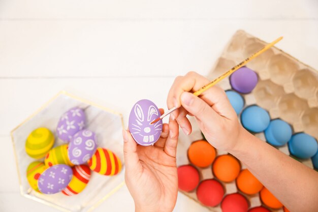 Mãos humanas pintando ovos de Páscoa.