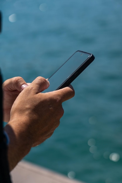 Mãos irreconhecíveis de jovem usando celular na rua