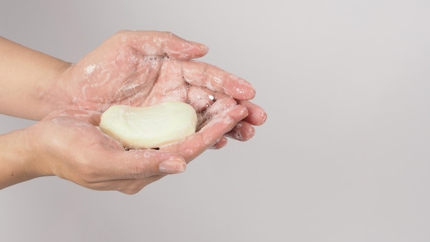 Mãos, lavagem gesto com sabão em barra e bolha de espuma em fundo branco.