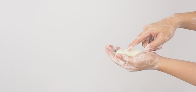 Mãos, lavagem gesto com sabão em barra e bolhas em fundo branco.