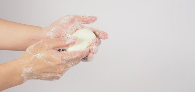 Mãos, lavagem gesto com sabão em barra e bolhas em fundo branco.