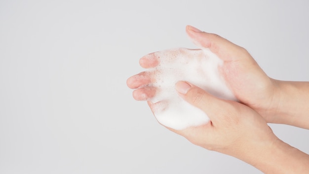 Mãos, lavagem gesto com sabonete de espuma em fundo branco.