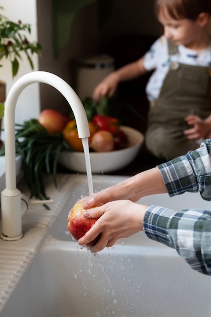 Foto mãos lavando maçã com criança embaçada no fundo