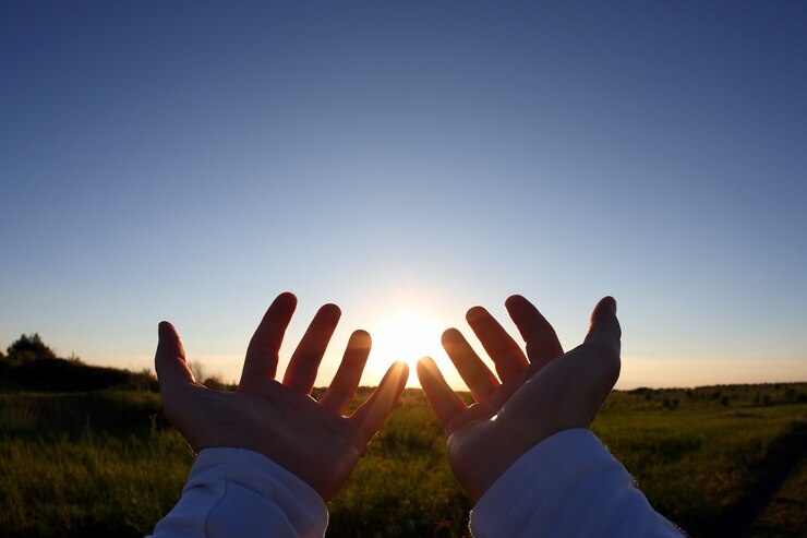 Mãos levantadas no fundo do pôr do sol