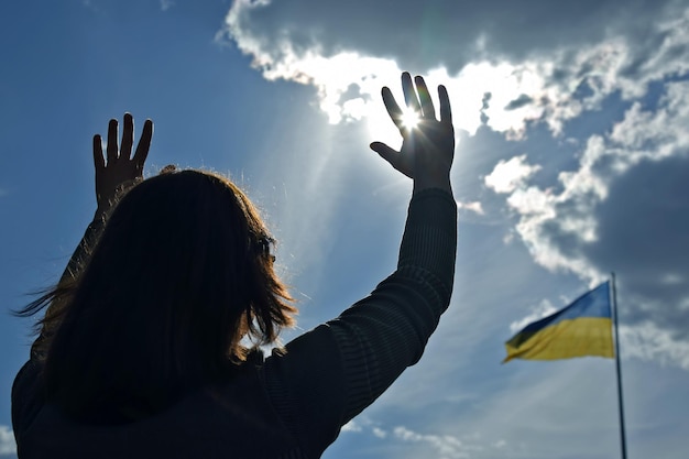 Foto mãos levantadas para o céu no contexto da bandeira da ucrânia oração por ajuda e bênçãos para o país da ucrânia proteção para a nação