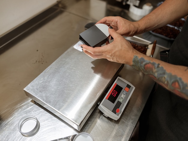 Mãos masculinas colocando uma jarra de metal com café na caixa preta