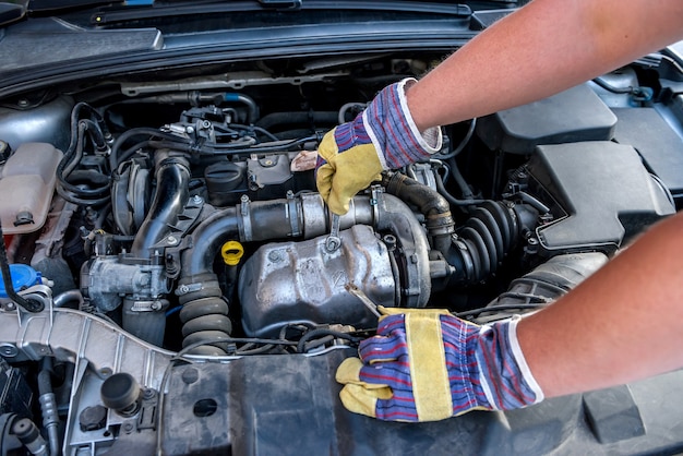 Mãos masculinas com chaves inglesas. conceito de serviço do carro. mãos em luvas de proteção contra motor de carro