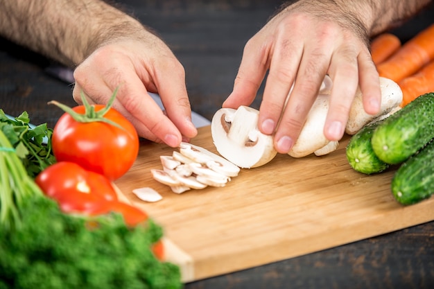 Mãos masculinas cortando vegetais para salada