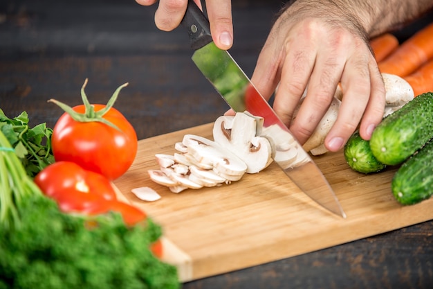 Mãos masculinas cortando vegetais para salada