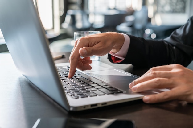 Mãos masculinas de gerente de escritório digitando no teclado do laptop closeup empresário trabalhando com laptop sem rosto mãos masculinas pressionando um botão no teclado na mesa de escritório de madeira conceito de trabalho