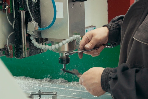 Mãos masculinas de trabalhador trabalhando com máquina cnc na fábrica com tornos, close-up